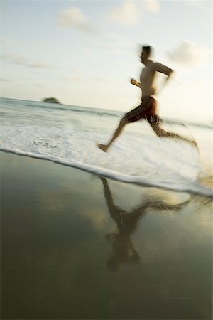 Profile of a man running on the beach Stock Photo - Premium Royalty-Free, Code: 640-01358464