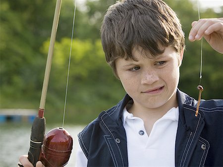 fashion boys 12 years - Close-up of a boy holding a fishing rod Stock Photo - Premium Royalty-Free, Code: 640-01358473