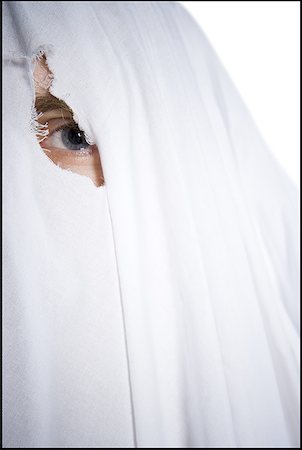 Portrait of a person looking through a hole in a sheet Stock Photo - Premium Royalty-Free, Code: 640-01358635