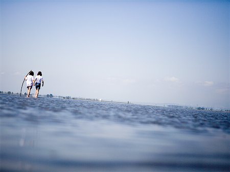 Rear view of two people wading in water Stock Photo - Premium Royalty-Free, Code: 640-01358639