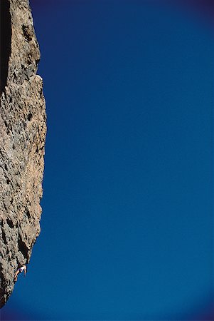 simsearch:640-01361581,k - Low angle view of a person climbing a steep rock formation Fotografie stock - Premium Royalty-Free, Codice: 640-01358747