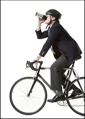 person on bike white background - Profile of a businessman cycling and holding from a mug Stock Photo - Premium Royalty-Free, Code: 640-01358802