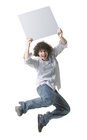 Portrait of a teenage boy holding a blank sign and jumping in mid- air Stock Photo - Premium Royalty-Free, Code: 640-01358844