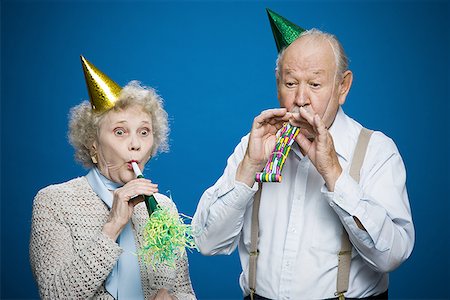 Older couple with noisemakers and party hats Stock Photo - Premium Royalty-Free, Code: 640-01358935