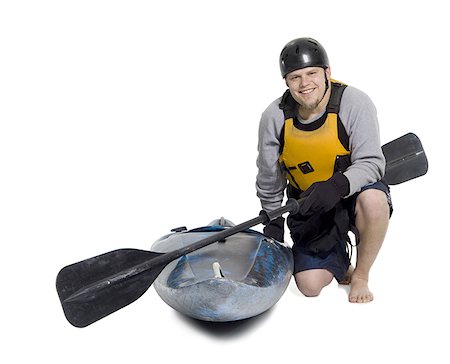 Portrait of a young man kneeling beside a kayak Stock Photo - Premium Royalty-Free, Code: 640-01359131