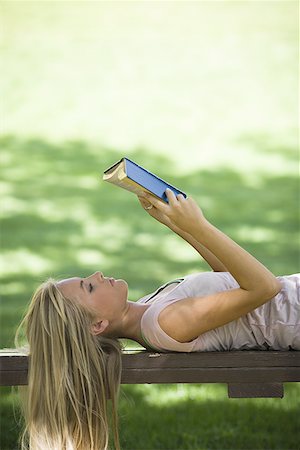 Young woman lying on a bench and reading a book Stock Photo - Premium Royalty-Free, Code: 640-01359146