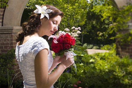 Side profile of a young woman smelling flowers Stock Photo - Premium Royalty-Free, Code: 640-01359189