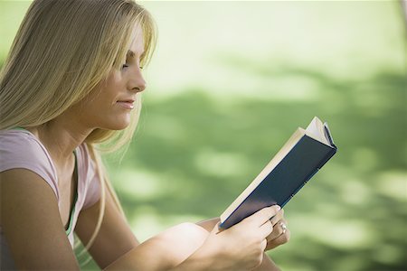 Profile of a young woman reading a book in a park Stock Photo - Premium Royalty-Free, Code: 640-01359190