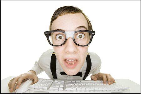 shocked teen computer - Boy sitting at keyboard with tape on eyeglasses Stock Photo - Premium Royalty-Free, Code: 640-01359313