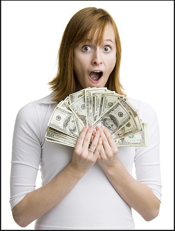 Portrait of a young woman holding fanned out dollar bills Stock Photo - Premium Royalty-Free, Code: 640-01359323