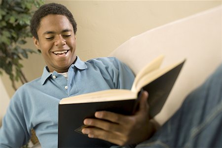 simsearch:640-01362028,k - Teenage boy reading a book and smiling Fotografie stock - Premium Royalty-Free, Codice: 640-01359405