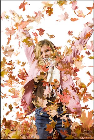 Young girl playing in fallen leaves Stock Photo - Premium Royalty-Free, Code: 640-01359402