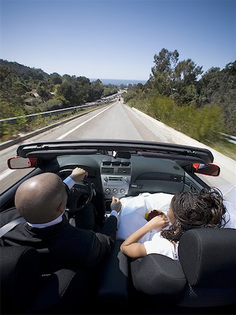 Vue arrière d'un couple de jeunes mariés dans une voiture décapotable Photographie de stock - Premium Libres de Droits, Code: 640-01359452