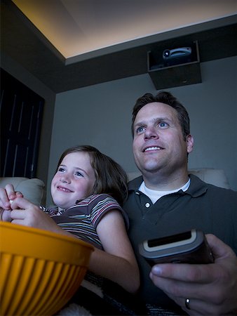 family watching tv together with popcorn - Father and daughters watching movie in home theater Stock Photo - Premium Royalty-Free, Code: 640-01359559