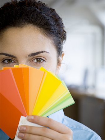 Portrait of a young woman holding color swatches in front of her face Stock Photo - Premium Royalty-Free, Code: 640-01359563