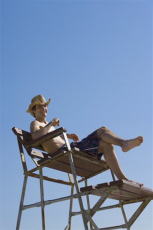 simsearch:640-01364192,k - Low angle view of a young man sitting on a lifeguard chair Foto de stock - Royalty Free Premium, Número: 640-01359576