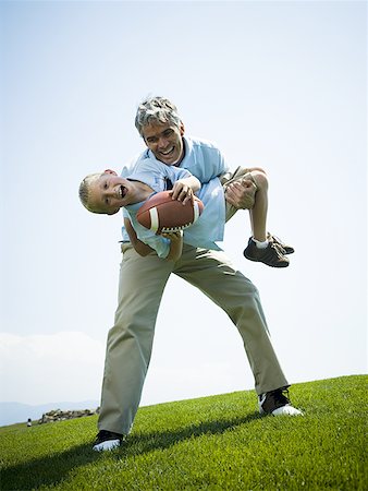 dad and kid playing football - Portrait of a man carrying his son Stock Photo - Premium Royalty-Free, Code: 640-01359623