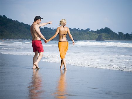 Mid adult couple holding hands and walking on the beach Stock Photo - Premium Royalty-Free, Code: 640-01359632