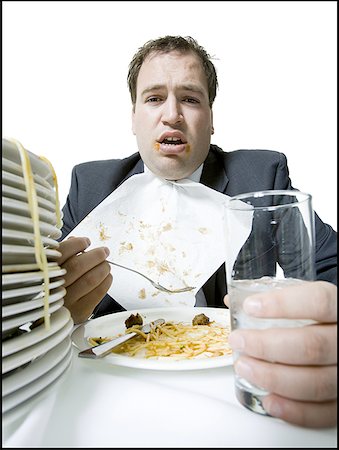 Portrait of a young man overeating at the dining table Stock Photo - Premium Royalty-Free, Code: 640-01359690