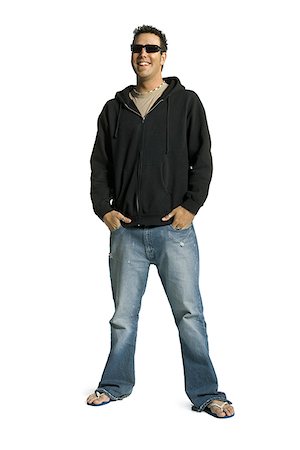 flip flops blue jeans - Young man standing with his hands in his pockets and smiling Stock Photo - Premium Royalty-Free, Code: 640-01359704