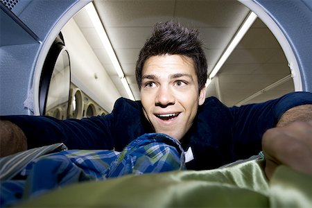 Man inside dryer at Laundromat with clothing Stock Photo - Premium Royalty-Free, Code: 640-01350009