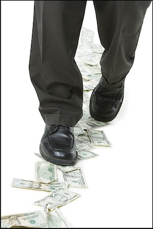 Low section view of a businessman walking on money Stock Photo - Premium Royalty-Free, Code: 640-01350123