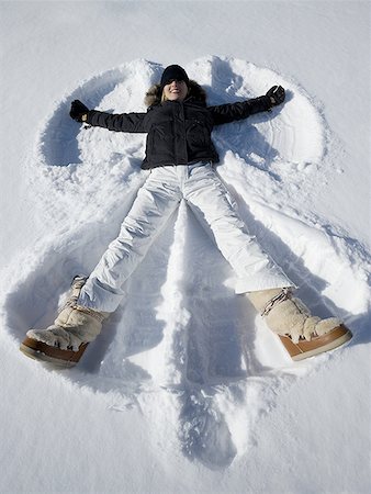 snow angel - High angle view of a young woman lying in snow making a snow angel Stock Photo - Premium Royalty-Free, Code: 640-01350177