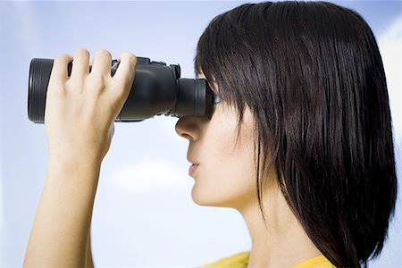 simsearch:700-01695607,k - Profile of a young woman looking through a pair of binoculars Fotografie stock - Premium Royalty-Free, Codice: 640-01350307