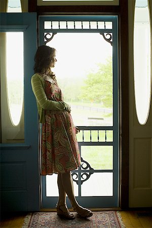 Profile of a woman leaning against a door and looking away Stock Photo - Premium Royalty-Free, Code: 640-01350324