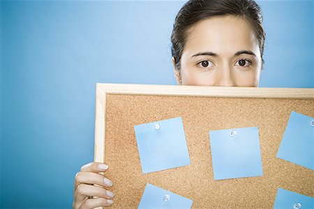 Close-up of a young woman holding a bulletin board against her face Stock Photo - Premium Royalty-Free, Code: 640-01350320