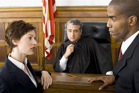 defy - Two lawyers standing face to face in front of a male judge in a courtroom Stock Photo - Premium Royalty-Free, Code: 640-01350334
