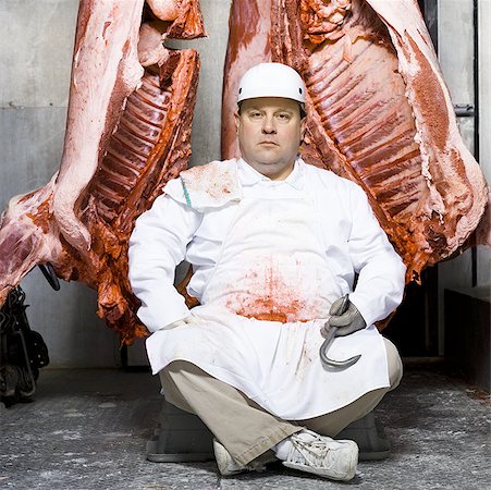 Butcher sitting with carcass and meat hook Stock Photo - Premium Royalty-Free, Code: 640-01350398