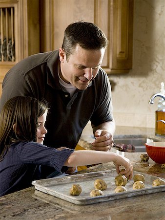 simsearch:640-01357998,k - Girl in kitchen with man baking cookies Stock Photo - Premium Royalty-Free, Code: 640-01350450