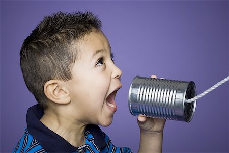 Gros plan d'un garçon criant dans un téléphone de boîtes de conserve Photographie de stock - Premium Libres de Droits, Code: 640-01350511