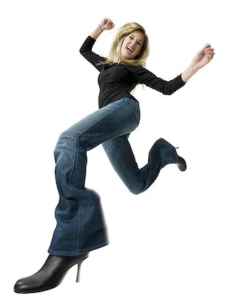 Low angle view of a young woman jumping with her arms raised Stock Photo - Premium Royalty-Free, Code: 640-01350914