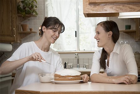 Close-up of a mother icing a cake with her daughter Stock Photo - Premium Royalty-Free, Code: 640-01350911