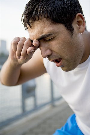 Close-up of a mid adult man wiping sweat from his face Stock Photo - Premium Royalty-Free, Code: 640-01350928