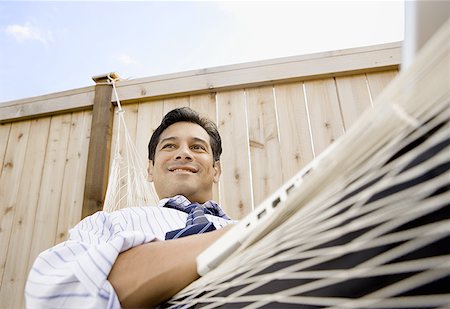 Low angle view of a businessman sitting on a hammock Stock Photo - Premium Royalty-Free, Code: 640-01350988