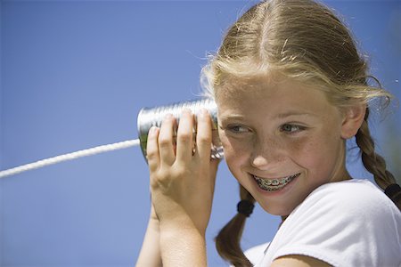 Low angle view of a girl listening into a tin can phone Foto de stock - Royalty Free Premium, Número: 640-01351127