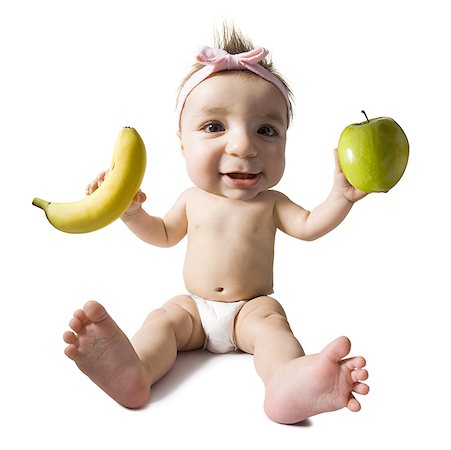 Baby girl with green apple and banana Stock Photo - Premium Royalty-Free, Code: 640-01351173