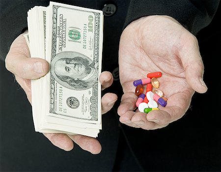 pharma - Mid section view of a man holding US Currency and pills simultaneously Stock Photo - Premium Royalty-Free, Code: 640-01351208