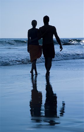 Rear view of a mid adult couple holding hands and walking on the beach Stock Photo - Premium Royalty-Free, Code: 640-01351347