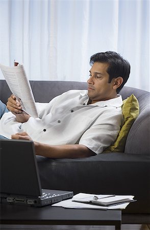 Man lying on a couch and reading a magazine Stock Photo - Premium Royalty-Free, Code: 640-01351668