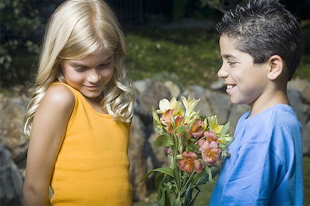 preteen boys smile long hair side - Profile of a boy giving flowers to a girl and smiling Stock Photo - Premium Royalty-Free, Code: 640-01351748