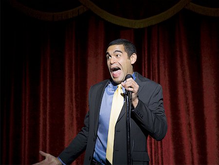 dark suit - Man in suit with microphone making funny faces Stock Photo - Premium Royalty-Free, Code: 640-01351891