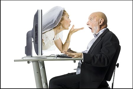 senior woman and blowing - Profile of a senior woman blowing a kiss through a computer monitor to her groom Stock Photo - Premium Royalty-Free, Code: 640-01352416
