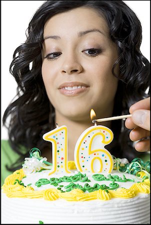 simsearch:640-01351032,k - Close-up of a teenage girl looking at a person lighting candles on her birthday cake Fotografie stock - Premium Royalty-Free, Codice: 640-01352456