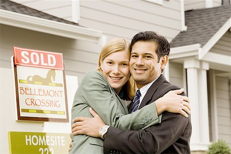 picture business woman house husband - Portrait of a couple hugging in front of house with 'Sold' sign Stock Photo - Premium Royalty-Free, Code: 640-01353039