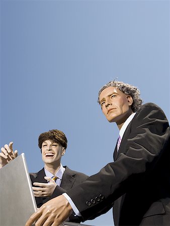 Low angle view of two mannequins portraying businessmen using a laptop Foto de stock - Sin royalties Premium, Código: 640-01353066