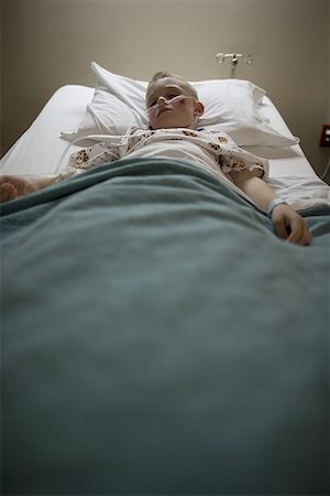 High angle view of a boy lying in a hospital bed breathing through a tube Stock Photo - Premium Royalty-Free, Code: 640-01353230